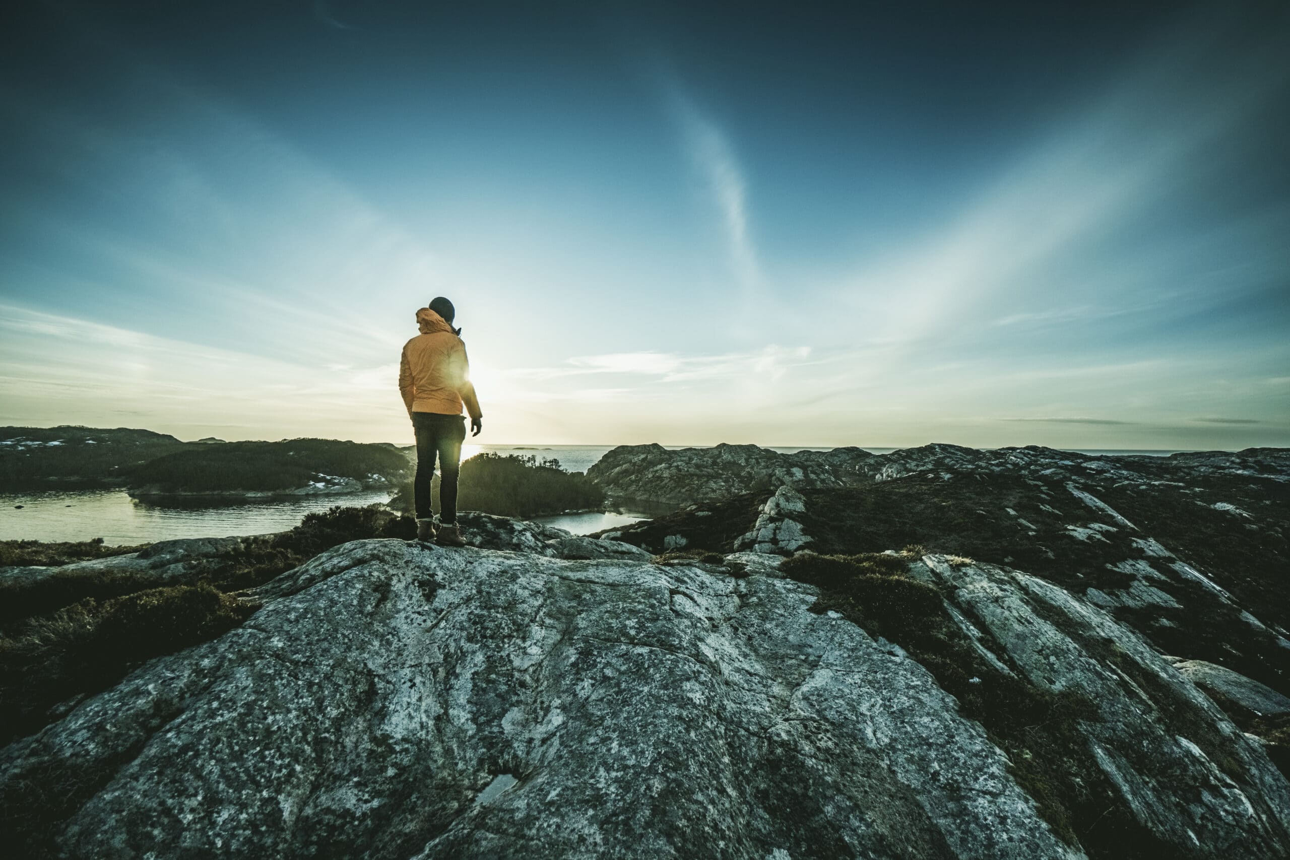 Mann som står og ser ut over et fjordlandskap.