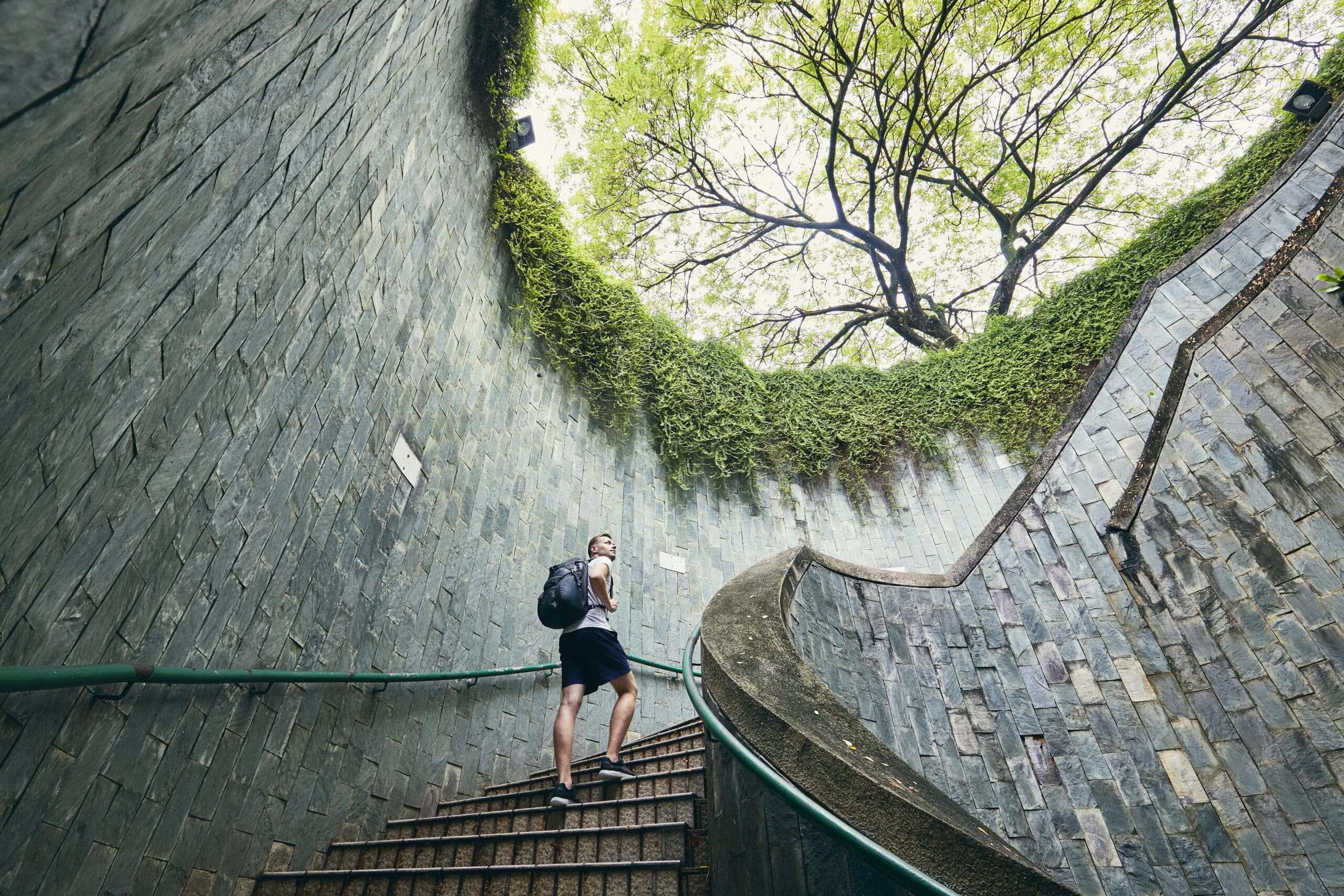Mann går opp spiraltrapp med utsikt til tretopper