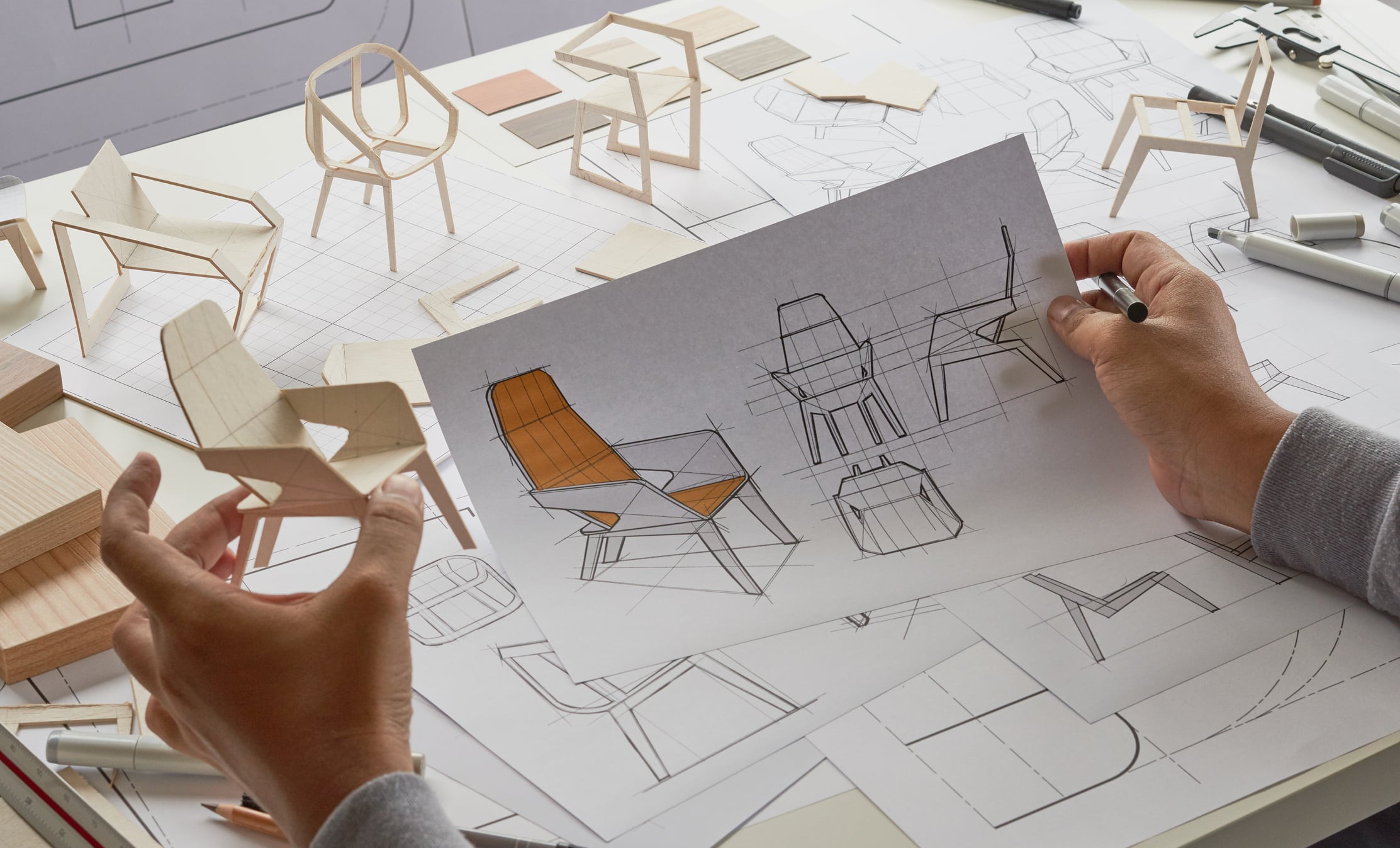 Bilde av designer som skisser og lager modeller av nye møbler.
