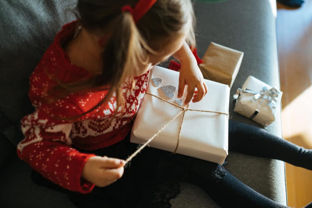 Bildet viser et barn som åpner en gave for å illustrere saken Mer miljøvennlige gaver til barn. 