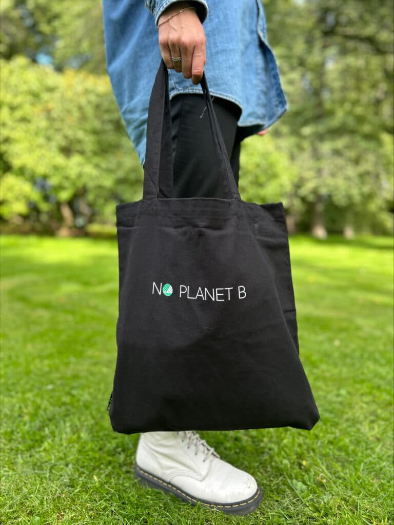 Bærer på et svart svanemerket handlenett med "No Planet B" tekst